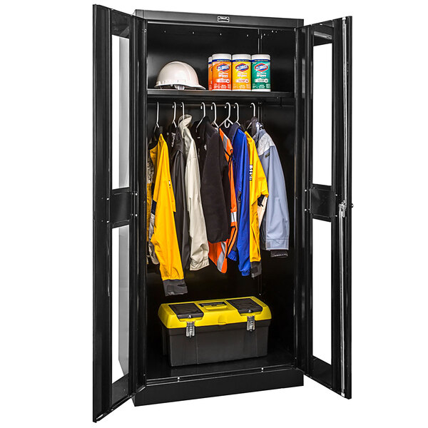 A black Hallowell metal wardrobe cabinet with Safety-View doors filled with clothes.