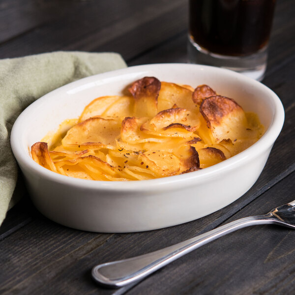 An ivory oval baker dish filled with potatoes on a table.