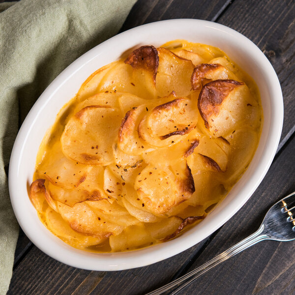 A Hall China oval baker dish filled with food and a fork.