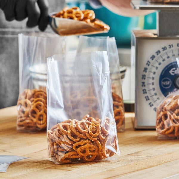 A person putting pretzels into a Choice plastic food bag.