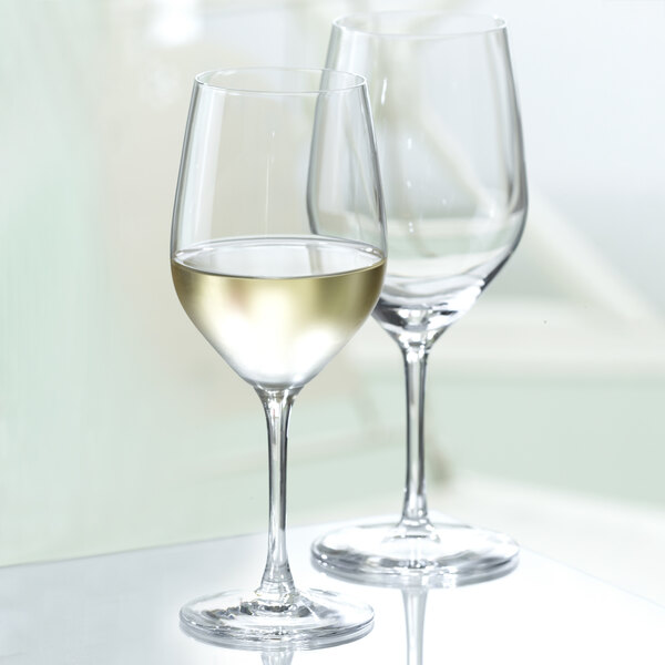 A close-up of two Stolzle white wine glasses filled with white wine on a table.