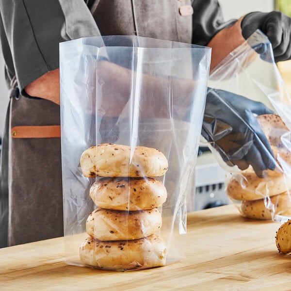 A person in gloves putting a bagel in a Choice plastic bag.