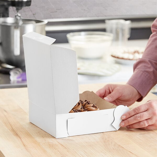 A person opening a white pie box.