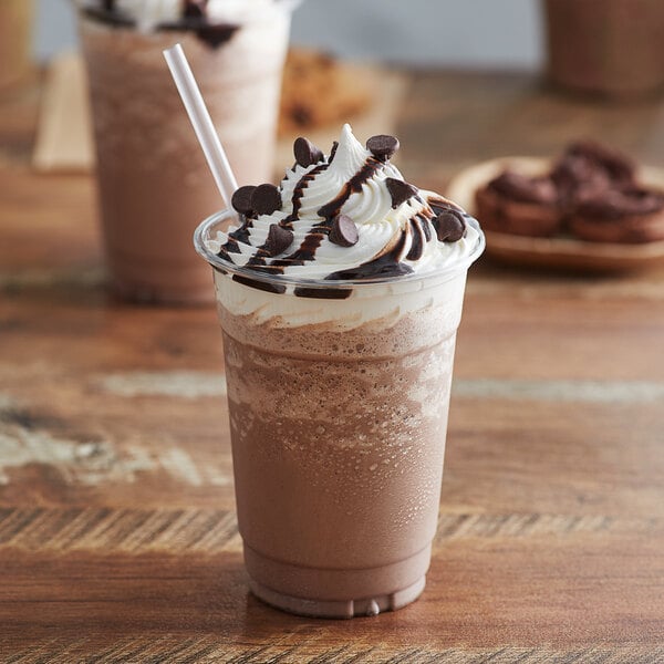 A close-up of a chocolate mocha drink with whipped cream and chocolate chips with a straw.