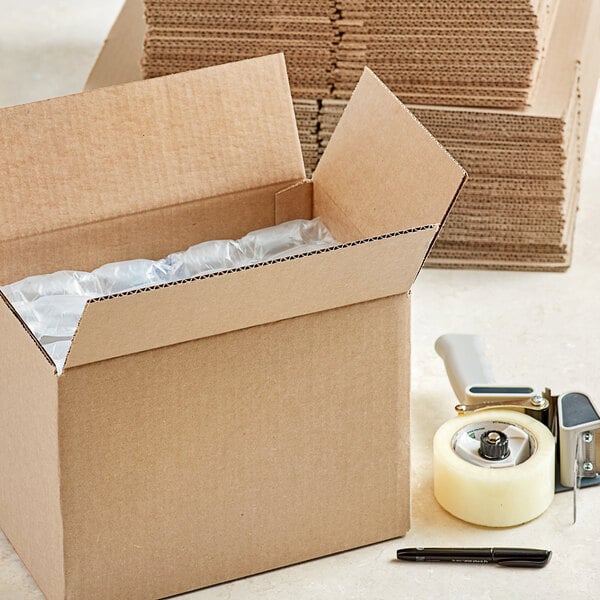 A Lavex cardboard shipping box on a table with a tape gun and a pen.