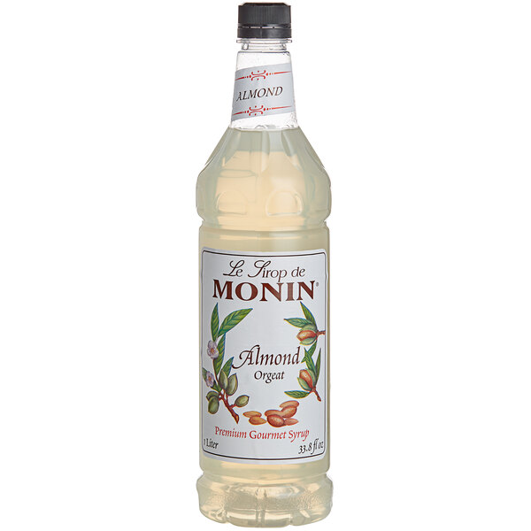 A case of four Monin Premium Almond Flavoring Syrup bottles with labels.