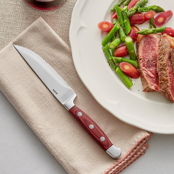 A plate of food with a steak knife on it next to a piece of meat.