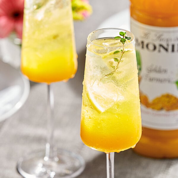 Two glasses of Monin Golden Turmeric drinks on a table.