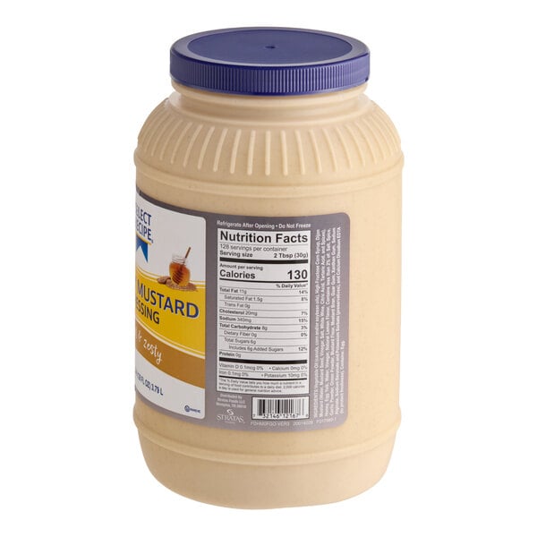 A large plastic jar with a blue lid containing a creamy yellow dressing, featuring a nutrition facts label and partial product branding visible.