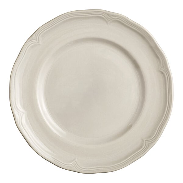 A close-up of an Acopa Condesa white porcelain plate with a scalloped white rim.