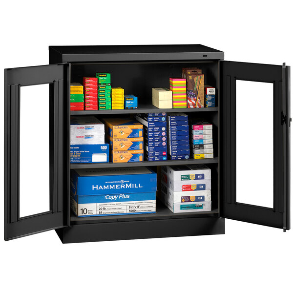 A black Tennsco storage cabinet with C-Thru doors storing boxes.