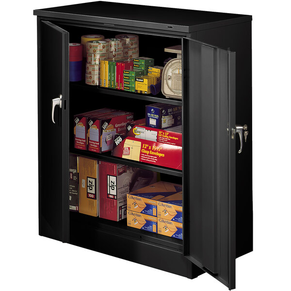 A black Tennsco storage cabinet with solid doors filled with boxes and cans.