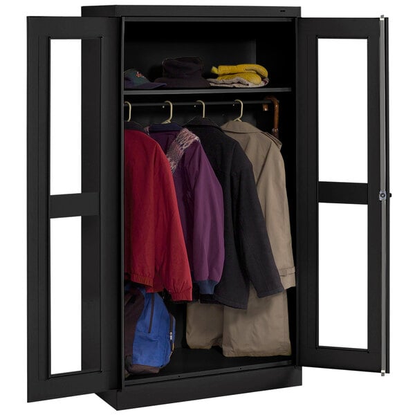 A black Tennsco wardrobe cabinet with C-thru doors holding coats.