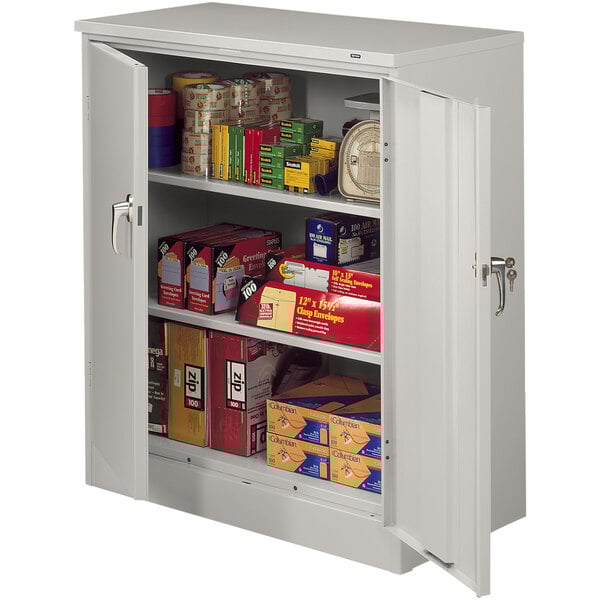 A light gray Tennsco deluxe storage cabinet with solid doors filled with items.