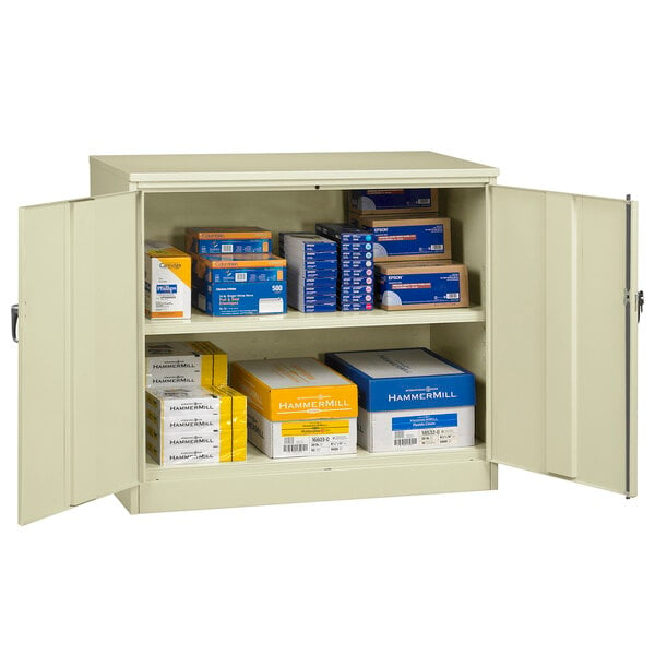 A Tennsco putty storage cabinet with solid doors open and filled with blue and yellow boxes.