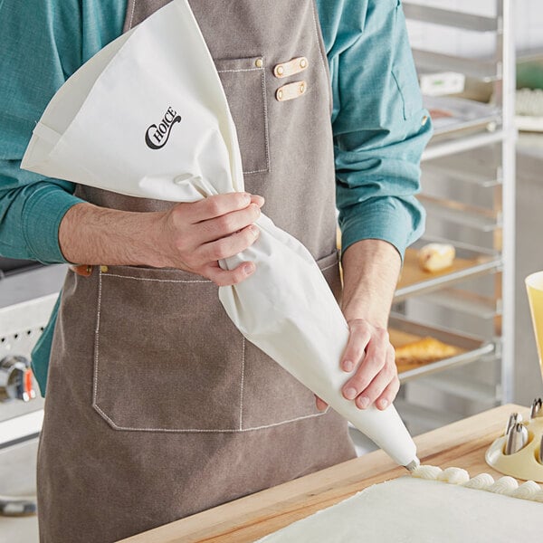 A person in an apron using a Choice plastic coated canvas pastry bag.