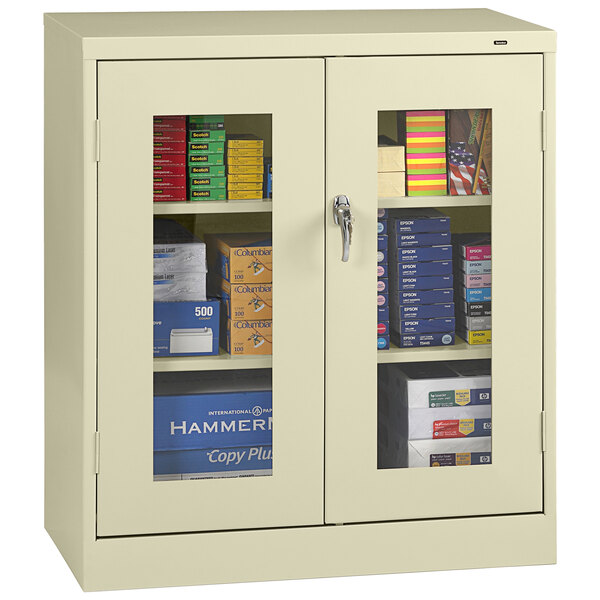A Tennsco standard storage cabinet with a C-thru door and glass doors filled with books and files.
