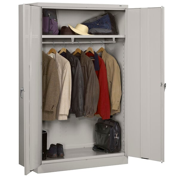 A light gray metal Tennsco jumbo wardrobe cabinet with solid doors holding clothes and shoes.