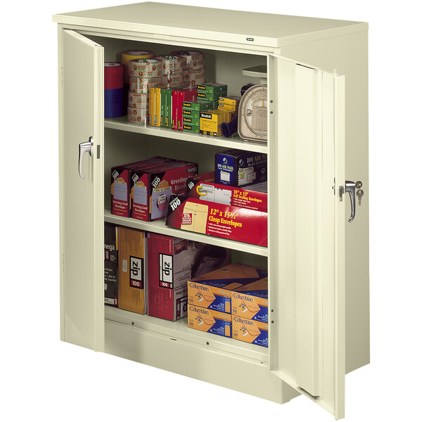 A putty Tennsco storage cabinet with shelves full of items.
