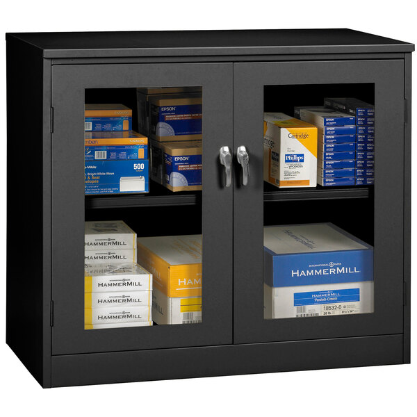 A black Tennsco jumbo storage cabinet with C-Thru doors filled with boxes with blue and white labels.