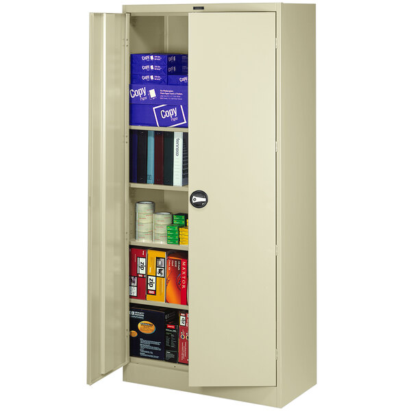 A Tennsco putty metal storage cabinet with solid doors open to reveal books inside.