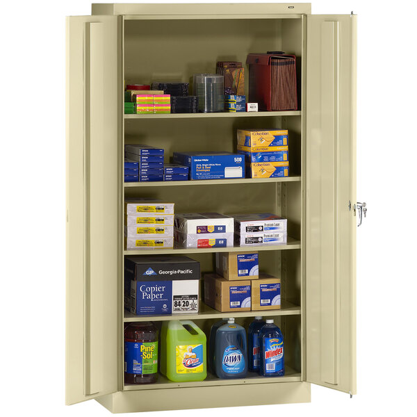 A Tennsco metal storage cabinet with solid doors filled with various items.