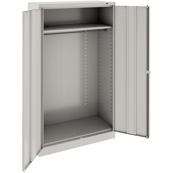 A light gray metal Tennsco wardrobe cabinet with solid doors.