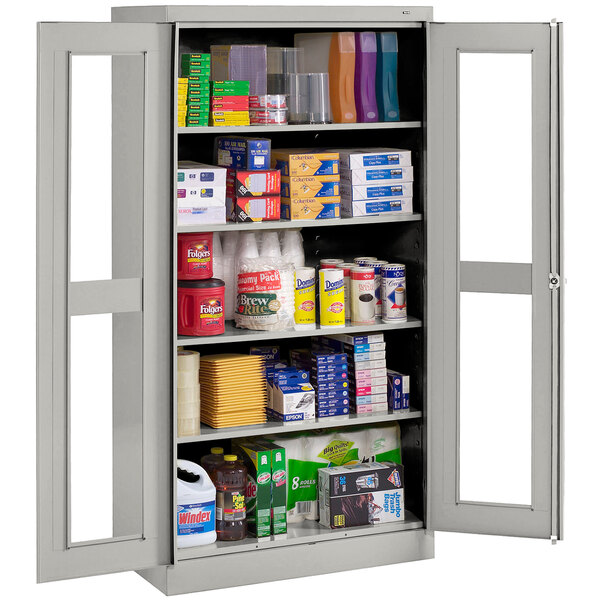 A Tennsco light gray metal storage cabinet with C-Thru doors filled with various items.