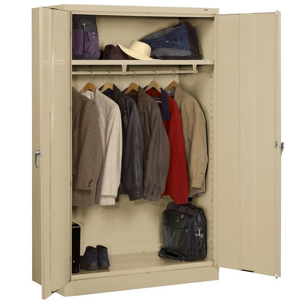 A sand metal Tennsco wardrobe cabinet with clothes and luggage.