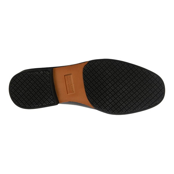 The image shows the bottom view of a black shoe sole with a textured, non-slip pattern and a brown section in the middle.