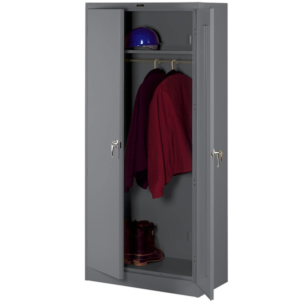 A dark grey Tennsco deluxe wardrobe cabinet with solid doors holding a red jacket and helmet.