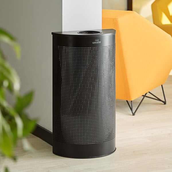 A black half round Lancaster Table & Seating decorative trash can on a white floor.