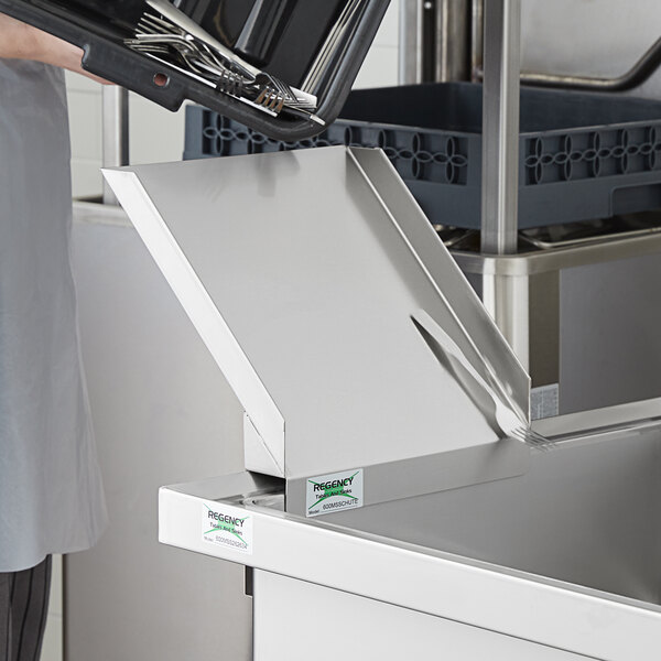 A person holding a tray with utensils soaking in a Regency mobile silverware sink bowl.