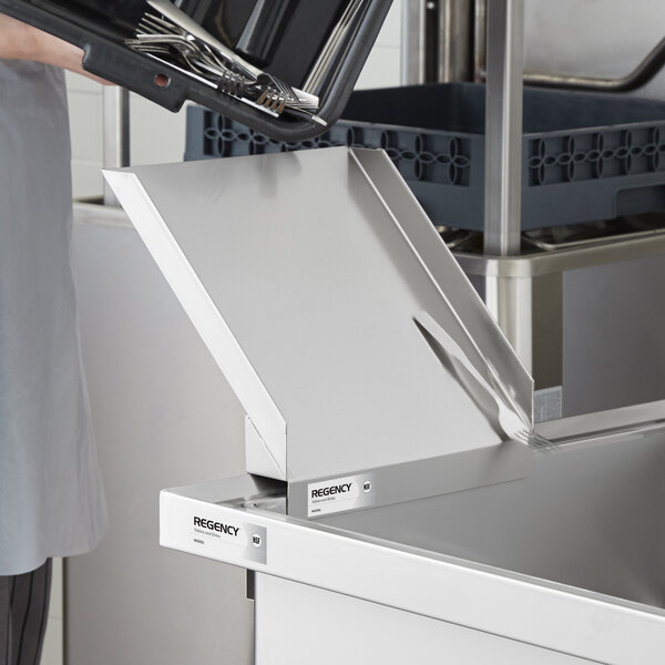 A stainless steel soaking sink with a detachable chute, shown in a commercial kitchen setting with utensils being emptied into it.