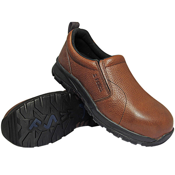 A pair of brown slip-on shoes with black soles, one shoe standing upright and the other lying on its side to display the tread pattern.