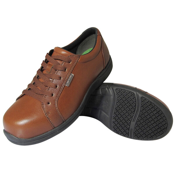 A pair of brown lace-up shoes with black non-slip soles, one shoe standing upright and the other lying on its side to show the sole.