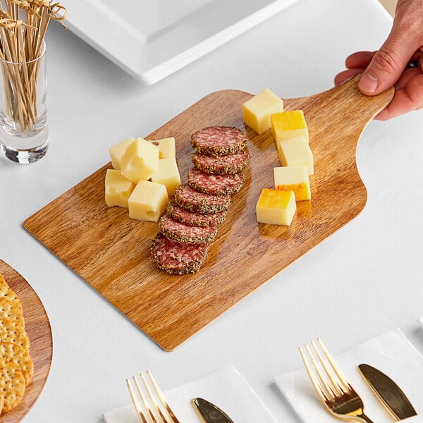 A person holding an Enjay marble and wood cake board with food on it.