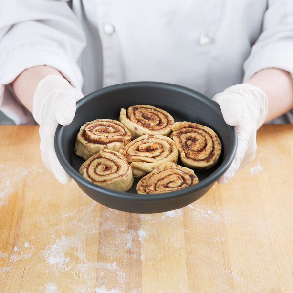 A person holding a pan of cinnamon rolls.