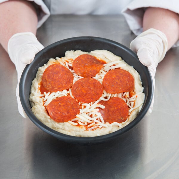 A pizza in a Chicago Metallic deep dish pizza pan.