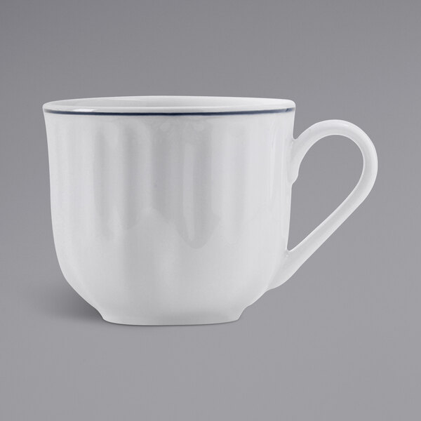 A white Tuxton china cup with a blue rim and embossed design.