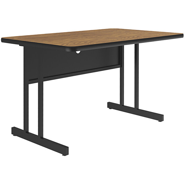 A Correll rectangular desk with a medium oak wood top and black base.