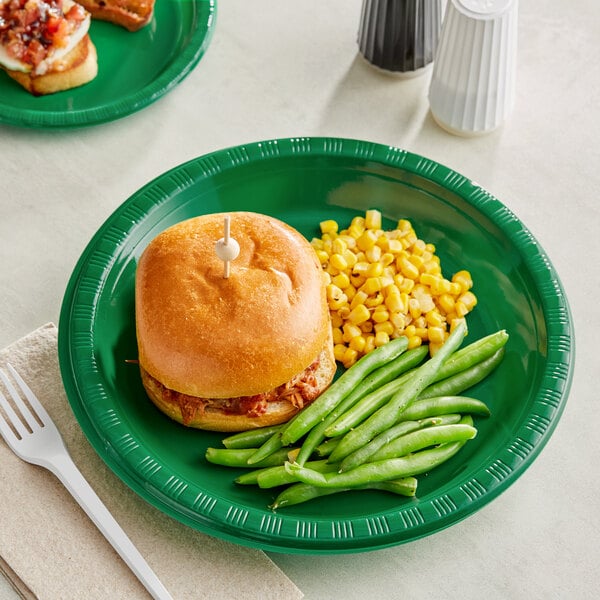 A Creative Converting emerald green plastic plate with a sandwich and corn on the cob on a table.