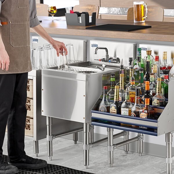 A man using an Advance Tabco underbar hand sink with glass rinser to fill a glass.