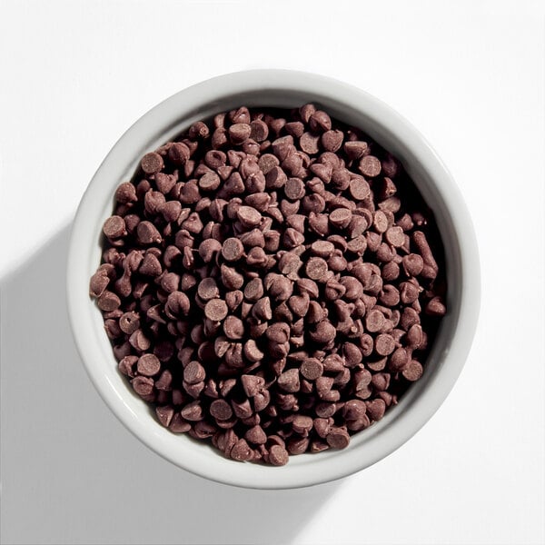 A white bowl filled with semi-sweet mini chocolate baking chips.