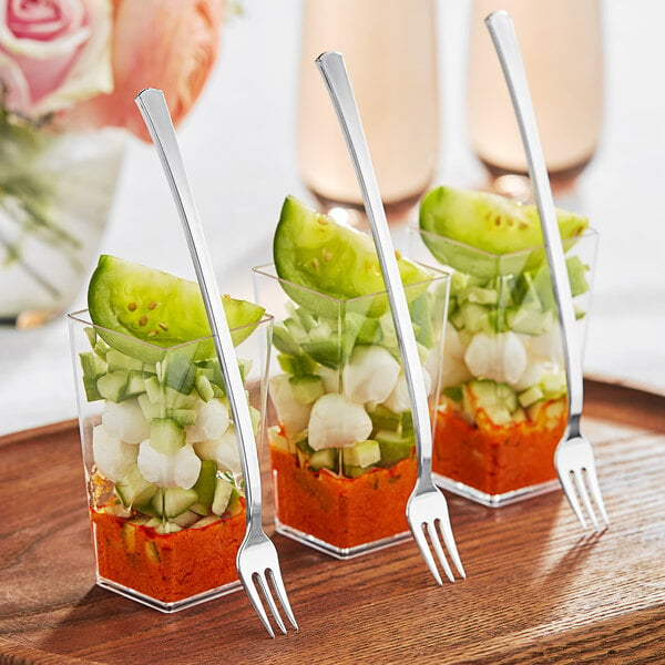 A table with small containers of food and Visions silver plastic forks.