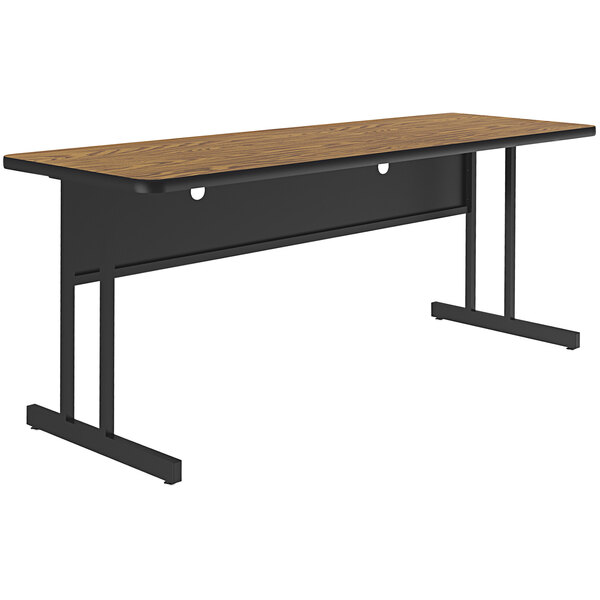 A rectangular medium oak Correll desk top on a black table base.