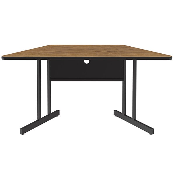 A trapezoid table with a medium oak top and black base.