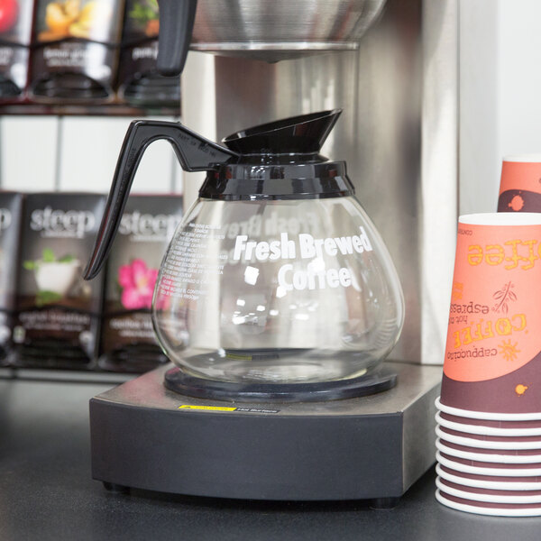 A Grindmaster glass coffee decanter with a black handle on a coffee maker.