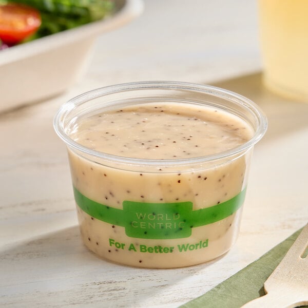 A clear 4 oz. compostable portion cup filled with salad dressing, branded with 'World Centric' and 'For A Better World' text.