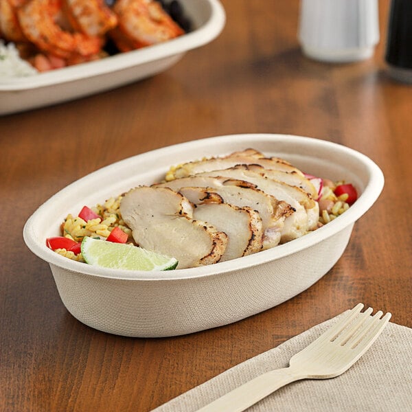 A World Centric compostable fiber bowl filled with meat and rice on a table.